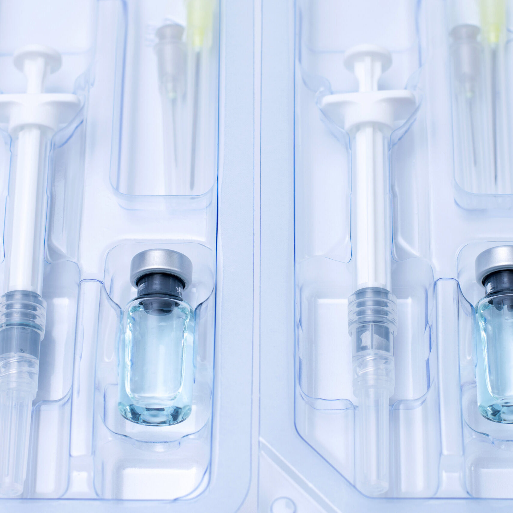 Covid-19, flu, coronavirus liquid vaccine vial bottle and syringe set in plastic package container preparing for injection on white background. Vaccination for fight Covid-19 virus concept.