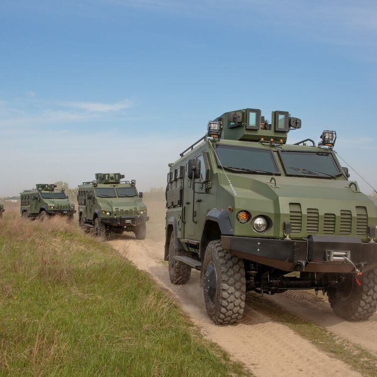 Armored vehicles driving down a dirt road.