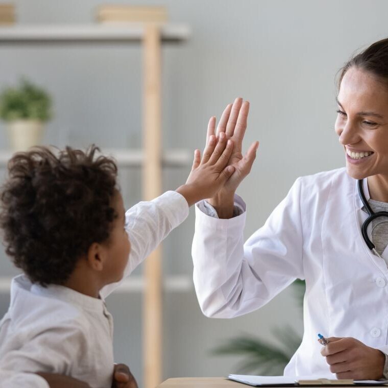 Woman Dr. high fiving child.