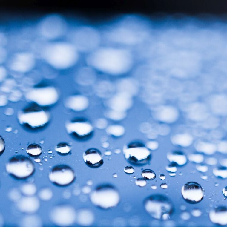 Hydrophobic films on light blue material with water droplets.