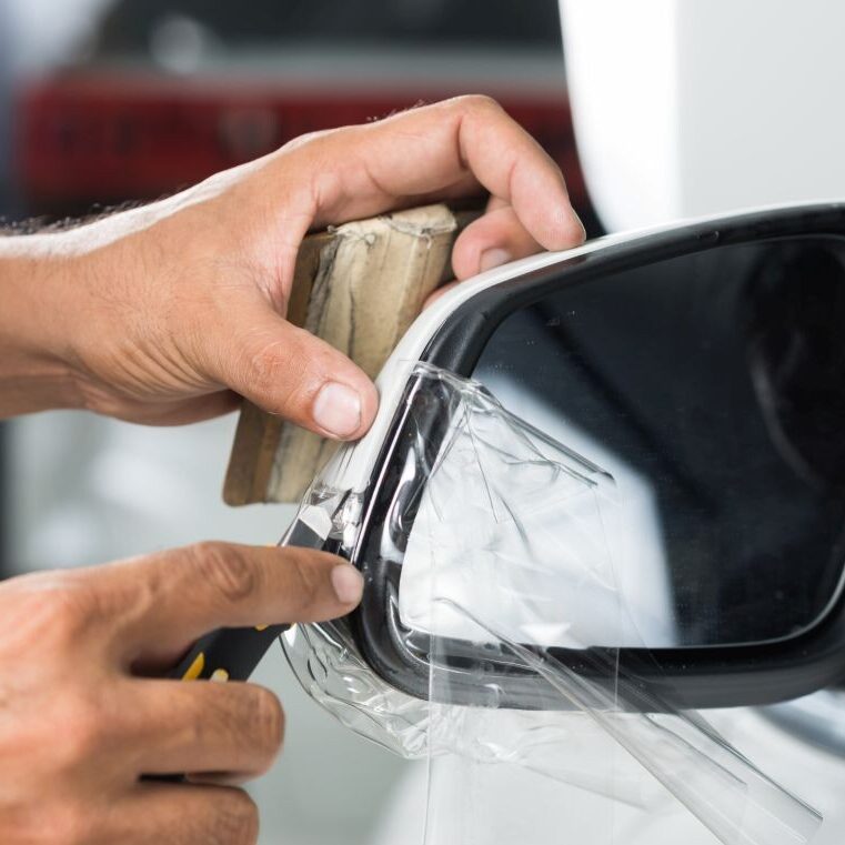 Paint protection film being installed on white car window.